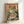 May include: A framed poster print leaning against a white wall on a white surface. The vintage-style artwork features a green frog with large orange eyes eating noodles from a colorful ramen bowl using chopsticks, set against a coral pink background with Japanese characters. The illustration has a weathered, retro aesthetic with muted colors and is displayed in a natural wood frame.