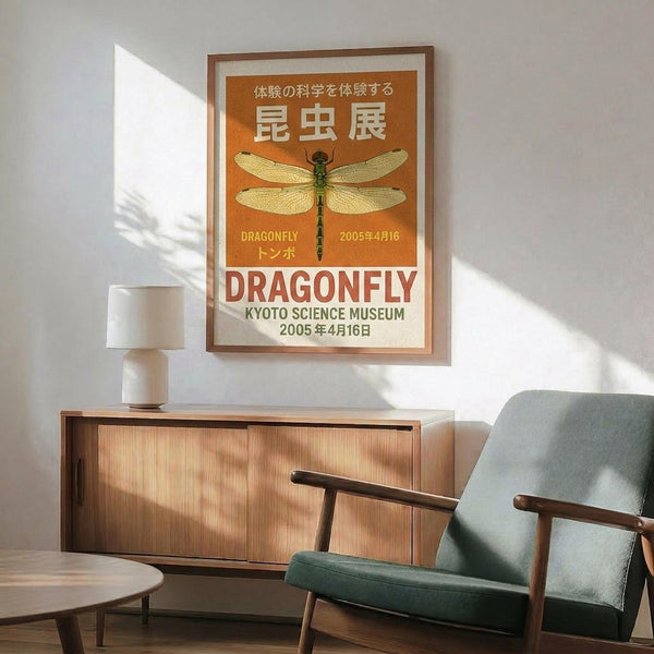 May include: Framed vintage-style poster with orange and cream background featuring detailed dragonfly illustration and Japanese text, displayed above mid-century wooden sideboard with white ceramic lamp in modern living room setting with sage green upholstered chair and round wooden coffee table