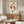May include: Framed artwork showing two reddish-brown koi fish swimming in a circular yin-yang pattern against a cream background, displayed above a mid-century modern walnut credenza in a minimalist living room with white curved chair, glass coffee table, and warm natural lighting