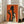 May include: Framed art print leaning against white wall next to beige sofa in bright living room. Orange background artwork shows black silhouette of woman holding wine glass and smaller light-colored figure with curly hair also holding glass. White frame, hardwood floors, large windows with natural light streaming in.