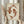 May include: Person holding framed wall art featuring two brown koi fish arranged in circular yin yang pattern on cream textured background, displayed in light wood frame. One hand also holds dried pampas grass stems. Soft neutral room setting with white curtains and beige clothing visible.