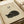 May include: Japanese-style art print featuring a sleeping black cat in minimalist ink style on cream textured paper, displayed in light wooden frame on neutral surface with beige ribbon accent. Asian characters visible at top of artwork.