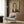 May include: Modern living room mockup showing framed reproduction of early 20th century portrait painting featuring woman with elongated neck, black hair, and red garment in distinctive modernist style. Cream armchair with geometric pillow, brass floor lamp, and dark wood paneled wall visible in staged interior setting.