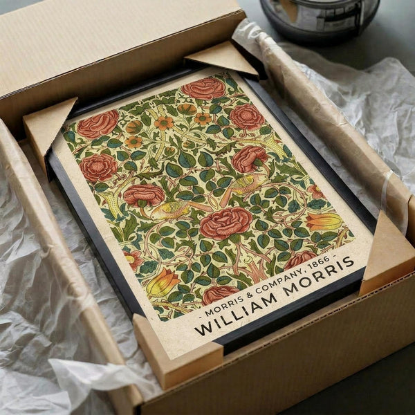 May include: Vintage botanical print with red roses and green foliage in ornate William Morris style pattern, displayed in black frame inside cardboard shipping box with tissue paper packaging on white surface