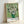 May include: Framed art print of Van Gogh's white roses in green vase against pale green background, displayed in light wood frame leaning against white wall. Post-impressionist painting reproduction features thick brushstrokes and vibrant colors. Print shows museum-style formatting with artist name and date at bottom.