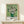 May include: Framed Van Gogh poster print featuring white roses in a green vase against a pale green background, displayed on a light wood console table with a small wrapped gift beside it. The artwork shows Van Gogh's characteristic brushwork style with thick paint texture. The print has "VAN GOGH" text at the bottom and appears in a thin natural wood frame against a cream colored wall.