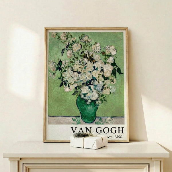 May include: Framed Van Gogh poster print featuring white roses in a green vase against a pale green background, displayed on a light wood console table with a small wrapped gift beside it. The artwork shows Van Gogh's characteristic brushwork style with thick paint texture. The print has "VAN GOGH" text at the bottom and appears in a thin natural wood frame against a cream colored wall.