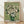 May include: Framed reproduction of Van Gogh's white roses painting in green glass vase against pale green background, displayed in light wooden frame leaning against white wall on natural wood floor with soft window light creating shadows