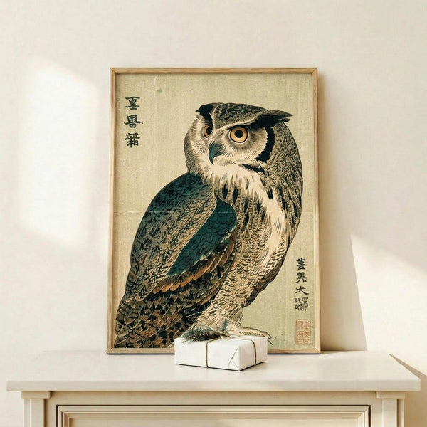 May include: Framed vintage Japanese woodblock print of an owl with detailed feathers in teal, brown, and cream tones, displayed on a light wood shelf against white wall. Japanese characters visible on aged beige background. Small white wrapped package sits beside the wooden frame.