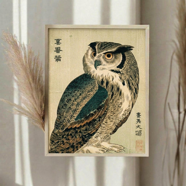 May include: Framed vintage Japanese woodblock print of an owl with detailed brown, teal and cream feathers, orange eyes, and black Japanese characters on aged paper background, displayed on white wall next to dried pampas grass in neutral room setting