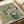 May include: Van Gogh's Roses painting print displayed in white matting with cream ribbon beside it. The artwork shows white roses in a green vase against a sage green background, painted in Van Gogh's characteristic thick brushstroke style. The print appears mounted in professional matting on a light wooden surface.