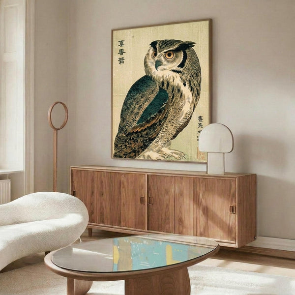 May include: Japanese woodblock print style owl artwork with orange eyes and detailed brown and teal feathers, displayed in thin frame above wooden sideboard in modern living room. White curved chair and glass-top coffee table visible. Vintage Asian calligraphy text on cream background poster.