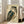 May include: Framed vintage Japanese woodblock print of an owl with detailed brown, teal, and cream feathers displayed in a bright living room. The owl has large golden eyes and intricate plumage against a beige background with Japanese text. The artwork leans against a white wall near a beige armchair and large windows with natural sunlight streaming in.