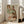 May include: Framed art print leaning against white wall next to beige sofa in bright living room. Print shows expressionist-style drawing of two embracing figures in earth tones - greens, browns, oranges - with distinctive angular faces and intertwined bodies. Light wood frame, large scale artwork positioned on wooden floor near windows.