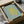 May include: Framed Matisse cut-out print featuring a golden yellow organic coral-like shape on sage green background, packaged in brown cardboard box with protective tissue paper. The artwork shows "MATISSE" and "THE CUT-OUTS" text at top, "HENRI MATISSE, NICE, 1947" at bottom. Black frame sits nestled in shipping materials on white surface.