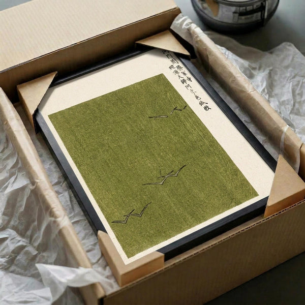 May include: Green textured print with Japanese calligraphy and minimalist bird silhouettes, displayed in black frame within cardboard shipping box surrounded by protective tissue paper and wooden dowels, showing unboxing presentation on white surface