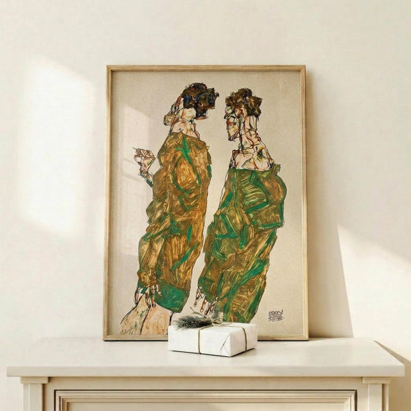 May include: Framed reproduction of an expressionist drawing showing two elongated male figures in flowing green and brown robes or garments, rendered in sketchy line work with watercolor washes. The artwork sits on a light wood shelf against a white wall, with a small wrapped gift box beside it. The piece features the angular, distorted style characteristic of early 20th century Austrian expressionism, with visible brushstrokes and muted earth tones.