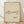 May include: Framed minimalist line drawing of a dachshund dog in black ink on beige textured paper background, displayed in light wood frame against white wall on wooden floor with natural lighting and shadows