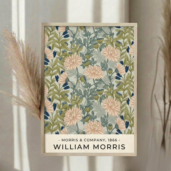 May include: Framed botanical poster with vintage William Morris floral pattern featuring pink chrysanthemums, blue and green foliage on cream background, displayed on white wall beside dried pampas grass stems and neutral curtains in soft natural lighting.