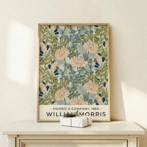 May include: Framed botanical poster featuring pink chrysanthemum flowers with green and blue-gray foliage on cream background, displayed on light wood console table with small wrapped gift, against neutral wall in home setting