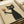 May include: Framed artwork showing a black cat with green eyes holding a wine glass filled with red wine, displayed on a white surface next to a white ribbon. The illustration has a vintage, textured appearance with rough brushstroke style on cream-colored paper, mounted in a simple light wood frame.