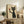 May include: Framed poster print featuring a stylized black cat with yellow eyes holding up a wine glass filled with red wine, displayed on a rustic wooden sideboard next to books, a fern plant, and ceramic vases in a cozy living room setting with neutral walls and brown leather furniture.