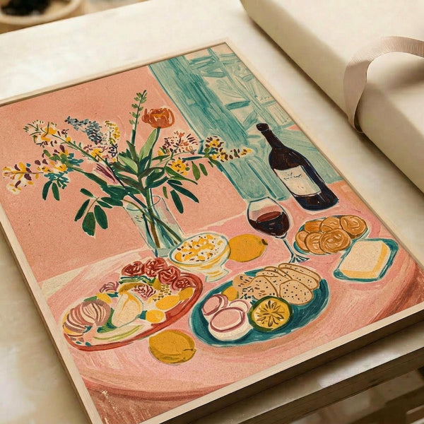 May include: Matisse-inspired still life print displayed in open art book on cream surface with ribbon. Artwork features vibrant coral pink background with wildflower bouquet in glass vase, wine bottle and glass, plates of sliced fruit, bread, cheese, and eggs. Colorful illustration uses bold brushstrokes and simplified forms characteristic of mid-century modern art style.
