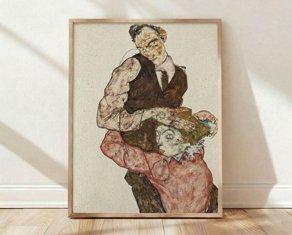 May include: Framed reproduction of an expressionist drawing showing two figures - a man in dark vest and light shirt looking directly forward, and a woman in coral-colored clothing with decorative headwear below him. The artwork features bold outlines, muted earth tones, and characteristic early 20th century Austrian art style. The print is displayed in a light wood frame against white walls on wooden flooring with natural window light casting shadows.