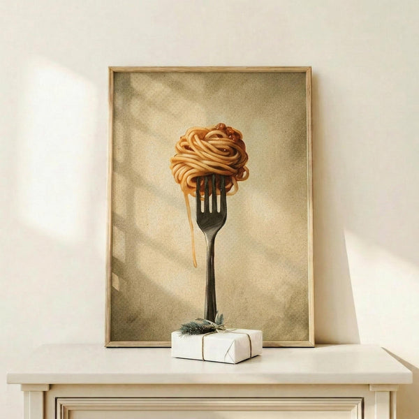 May include: Framed kitchen wall art showing spaghetti noodles twirled on a black fork against a vintage sepia background with soft clouds. The golden pasta appears to drip slightly from the fork tines. Displayed on a light wood shelf next to a small wrapped gift box with twine and greenery sprig. The frame has a thin natural wood border and the overall style is realistic with warm, muted tones.