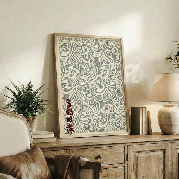 May include: Framed artwork featuring intricate wave patterns in sage green lines on cream background with red Japanese characters, displayed on rustic wooden sideboard alongside fern plant, ceramic vase, and books in neutral-toned living room setting