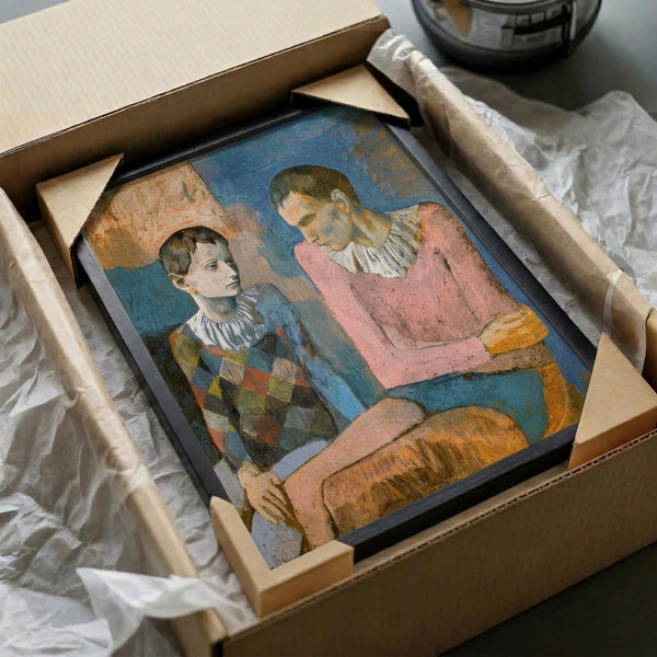 May include: Framed reproduction of early 20th century painting showing two figures in colorful clothing - one in checkered pattern, another in pink top - carefully packed in cardboard shipping box with protective tissue paper and wooden frame supports visible around edges.
