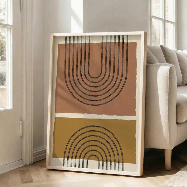 May include: Modern abstract art print displayed in light wood frame on floor next to beige sofa in bright living room. Artwork features geometric rainbow arches in black lines on terracotta orange and mustard yellow color blocks with white background. Natural sunlight streams through tall windows creating shadows on white walls and hardwood floors.