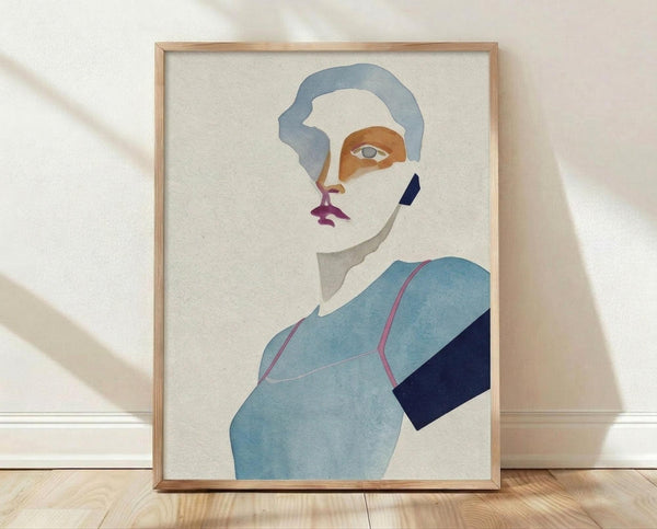 May include: Framed abstract portrait print leaning against white textured wall on light wood floor. Artwork shows stylized figure with blue-gray hair, orange and white face sections, purple lips, and blue clothing with dark navy accent. Natural wood frame, soft window light creates diagonal shadows on wall.