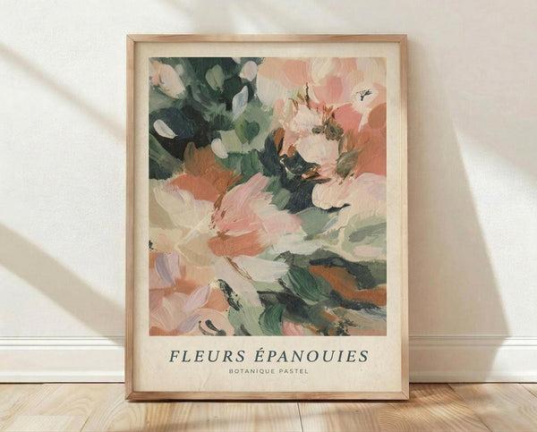 May include: Framed botanical art print with abstract painted flowers in soft pink, coral, and sage green brushstrokes displayed in light wood frame against white textured wall. Print shows impressionistic floral design with flowing paint strokes and French text below artwork. Frame sits on light wooden floor with natural window shadows cast across scene.