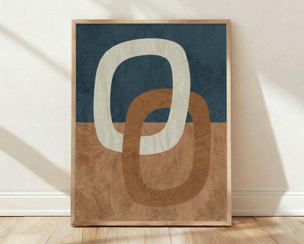 May include: Framed abstract art print featuring interlocking oval rings in cream, terracotta orange, and navy blue against a textured background. The wooden frame sits on light wood flooring against a white wall with natural shadows, showing the artwork's scale and modern minimalist style.