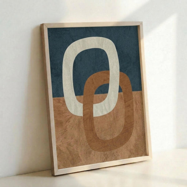 Abstract geometric artwork featuring two interlocking rounded rectangular rings in cream and terracotta orange colors. The background is split horizontally between deep navy blue on top and warm beige textured paper below. The piece is displayed in a thin natural wood frame, leaning against a white wall with soft shadows visible.
