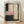 May include: Abstract modern art print in light wood frame leaning against white wall on wooden floor. Artwork features soft rectangular color blocks in pink, cream, and beige tones with bold black brushstrokes forming borders and a vertical line of black dots down the center. Painterly composition with layered translucent washes and gestural marks creates contemporary minimalist aesthetic.