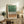 May include: Abstract watercolor artwork in light wood frame displaying green wash at top, vertical black line pattern in middle, and brown wash at bottom. Framed print sits on rustic wooden sideboard next to fern plant, ceramic vase, and stacked books in neutral-toned living room setting.
