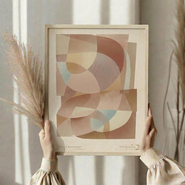 May include: Person holding framed abstract art print featuring overlapping geometric circles in warm earth tones of terracotta, beige, cream, and soft blue accents, displayed with dried wheat stems against neutral curtained background in natural lighting