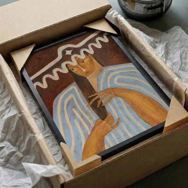 May include: Framed art print in cardboard shipping box with protective packaging materials. Artwork shows woman in blue and white striped clothing with flowing brown hair against warm brown background. Vintage-inspired portrait style with earthy tones of orange, blue, and brown. Black frame visible, surrounded by wooden corner protectors and white tissue paper.