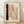 May include: Abstract art print in thin wooden frame leaning against white textured wall on light wood floor. Artwork features vertical black brushstroke on left, overlapping pink and sage green watercolor rectangles in center, vertical row of black dots, and curved black line on right, all on cream background.