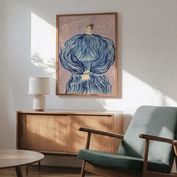 May include: Framed artwork showing a woman with flowing blue hair or fabric billowing around her against a pink background, displayed above a wooden sideboard with table lamp in a modern living room with mint green armchair and natural lighting creating shadow patterns on white wall.