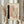 May include: Person holding framed abstract art print featuring vertical black brushstroke, pink and beige geometric shapes, and diagonal line of black dots on cream background. Light wood frame, held alongside dried pampas grass stems against soft beige curtains in natural lighting.