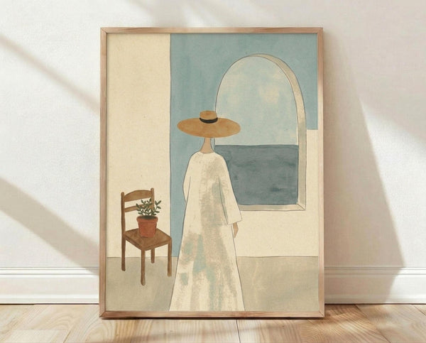 May include: A framed art print leaning against a white wall on light wood flooring. The artwork shows a figure in a white dress and wide-brimmed tan hat standing before an arched window overlooking the sea. A wooden chair with a small potted plant sits nearby. The piece features soft, muted colors in sage green, cream, and blue tones with a minimalist, contemporary illustration style in a light wood frame.