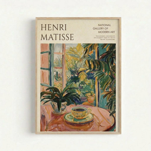 A framed exhibition poster featuring a vibrant Henri Matisse painting of an interior scene with a teacup and saucer on a pink table, surrounded by lush green tropical plants near a window. The artwork displays Matisse's characteristic bold brushstrokes and bright colors in yellows, greens, pinks, and blues. The poster includes museum text at the top identifying it as a National Gallery of Modern Art exhibition piece, all presented in a light wooden frame against a white wall.