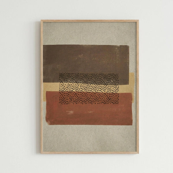 Framed abstract artwork with horizontal bands in brown, cream, and rust orange colors featuring a central dotted pattern. The piece has a textured, earthy appearance on beige paper within a light wood frame, displayed against a white wall.