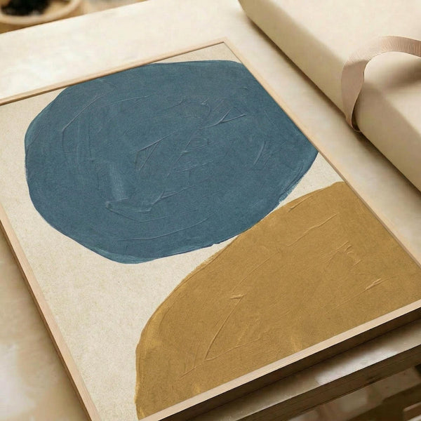 May include: Abstract minimalist poster print featuring large organic shapes in teal blue and mustard yellow on cream background, displayed in light wood frame on white surface next to rolled paper tube. Visible paint brush texture throughout the bold geometric forms creates handpainted appearance.
