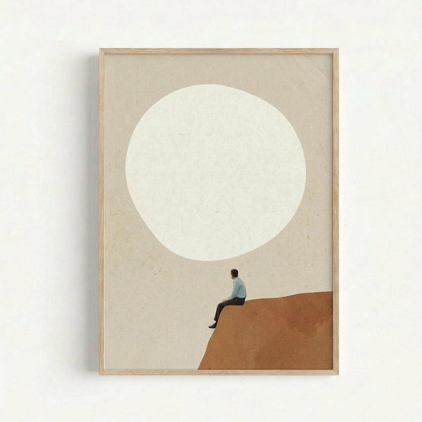 Framed minimalist art print featuring a small figure in light blue clothing sitting on the edge of a terracotta orange geometric shape, gazing up at a large white circle against a neutral beige background. The artwork is displayed in a light wood frame against a white wall, creating clean modern gallery styling with soft shadows.