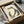 May include: Framed vintage Japanese woodblock print of a green frog with cream-colored belly sitting on what appears to be a lily pad or leaf, featuring traditional red seal stamp in upper left corner. The artwork is displayed in a black frame inside an open cardboard shipping box with protective white tissue paper and wooden dowels for safe transport.