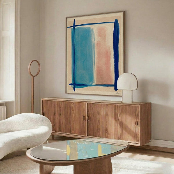 May include: Abstract art print with blue and pink rectangular color blocks crossed by dark blue brushstrokes, displayed in thin frame above mid-century walnut credenza. Modern living room setting with cream textured chair, brass floor lamp, oval glass coffee table, and soft natural lighting on neutral walls.